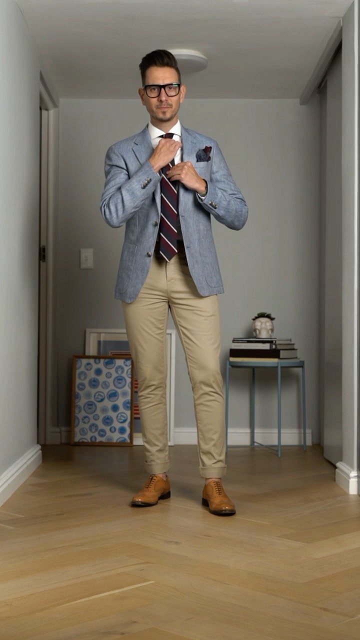 Man in a light blue blazer, striped tie, tan chinos, and brown leather shoes.