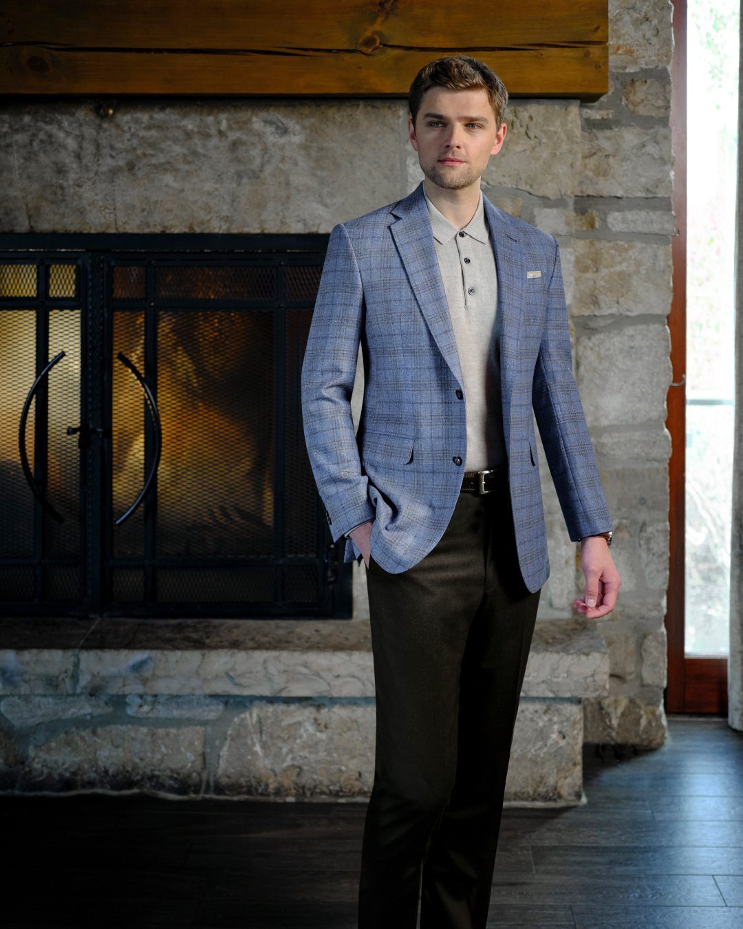 Man wearing a blue patterned sport coat over a beige knit polo and dark trousers.