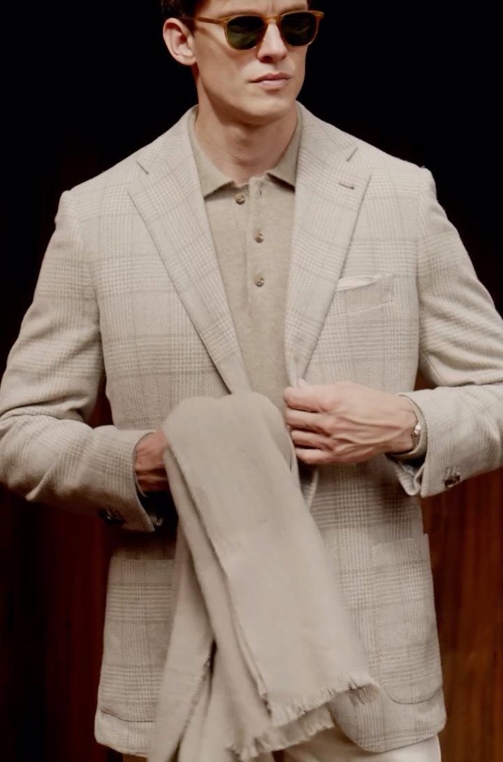 Man in a beige plaid blazer and polo shirt wearing sunglasses.