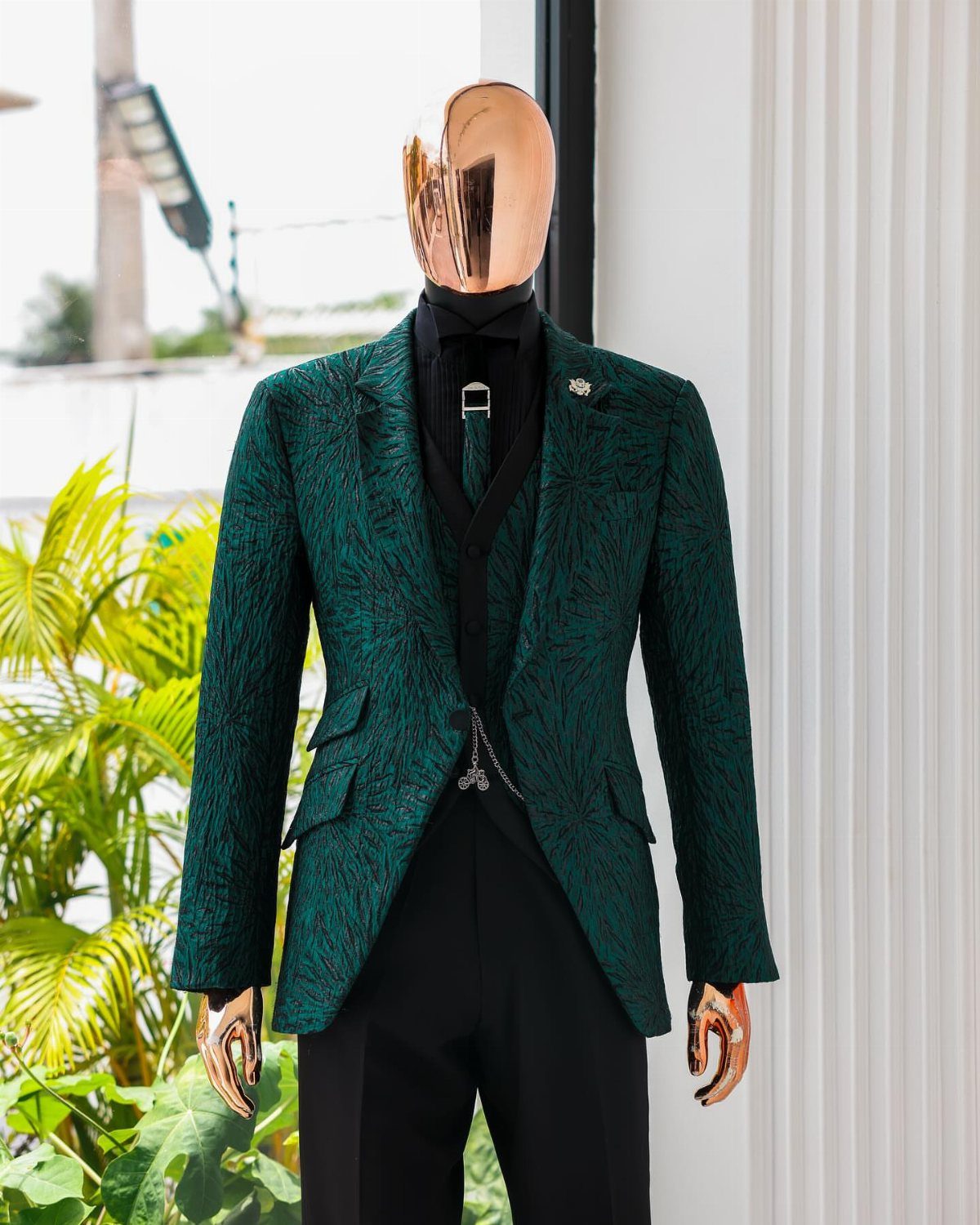 Emerald green textured suit jacket and waistcoat displayed on a gold mannequin.