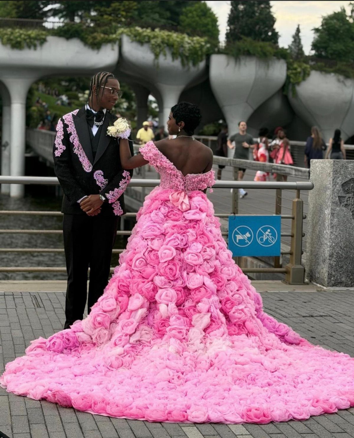 A man in a floral embroidered tuxedo and a woman in a pink rose gown.