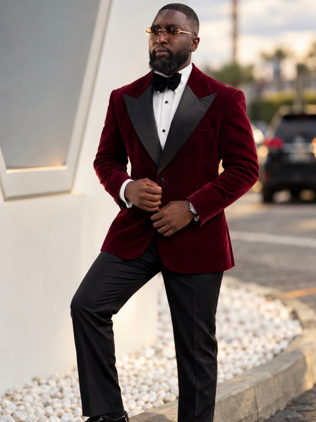 A man wearing a burgundy velvet tuxedo jacket with black lapels and a black bow tie.