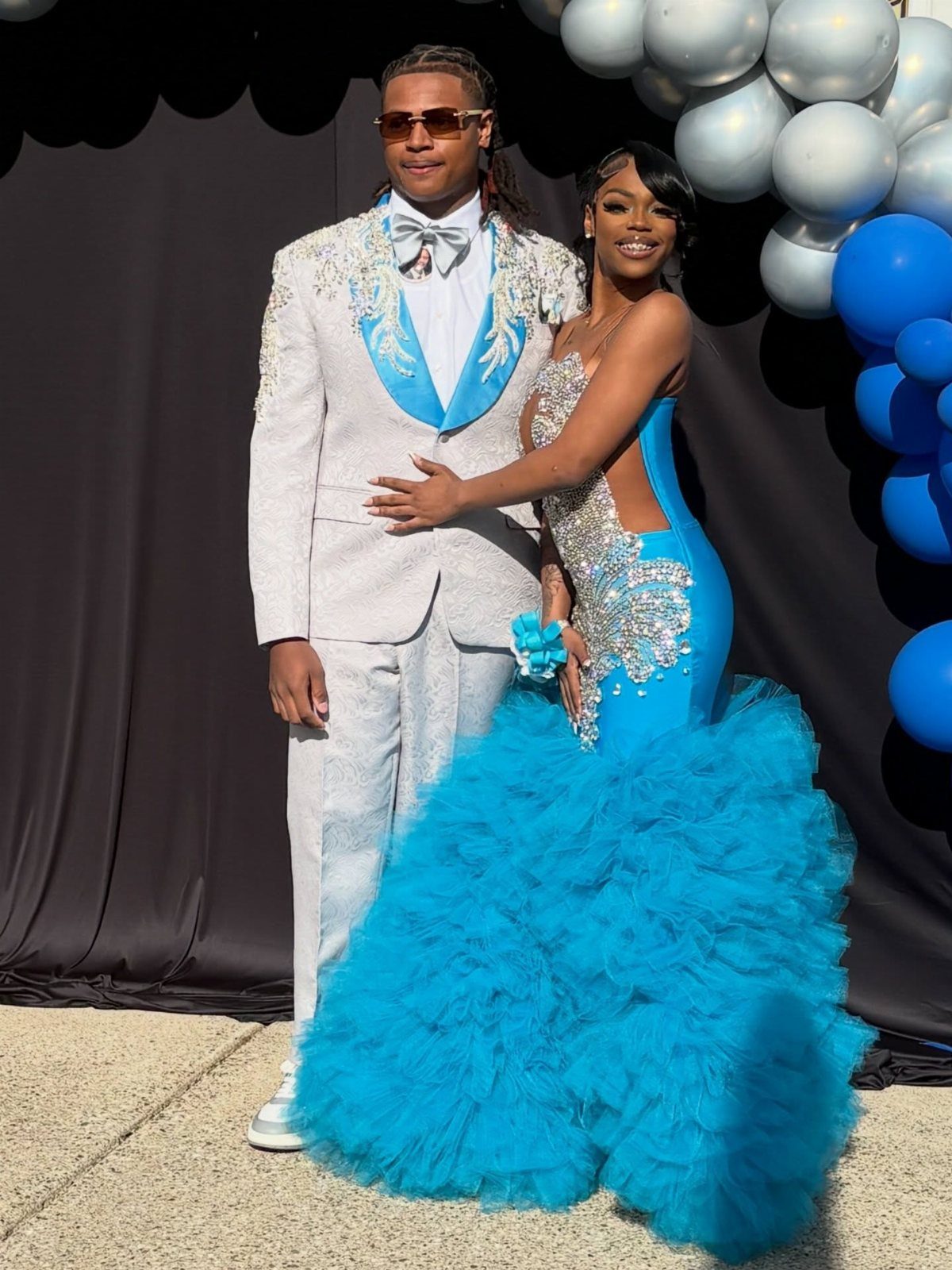 A man in a white and blue suit and a woman in a blue gown posing together.