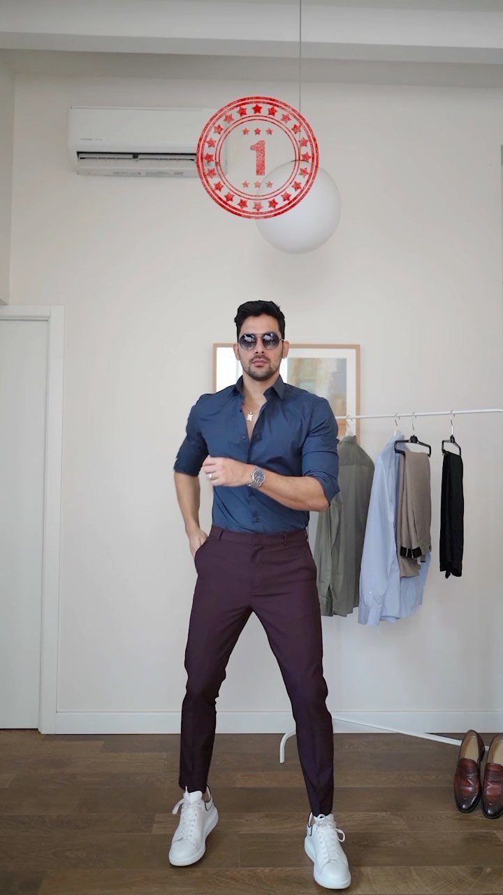 Man posing in a blue button-down shirt, burgundy trousers, and white sneakers.